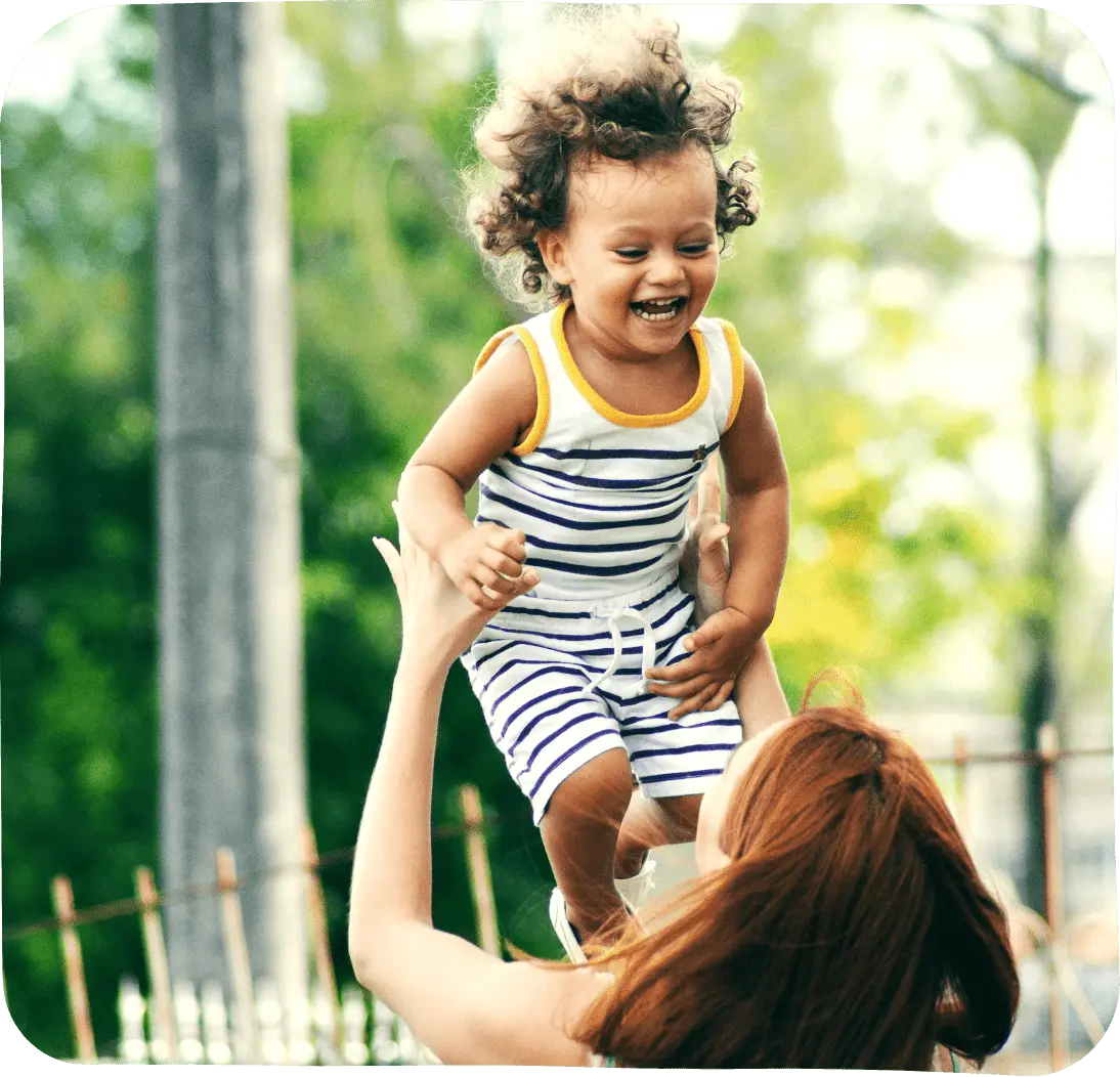 A Women holding up a laughing child in the air.