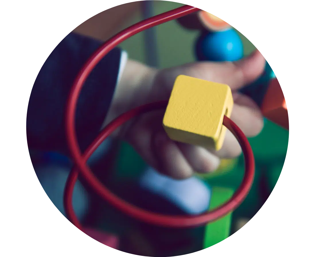 Photo of a part of a toy with a loop and a wooden square inside it.