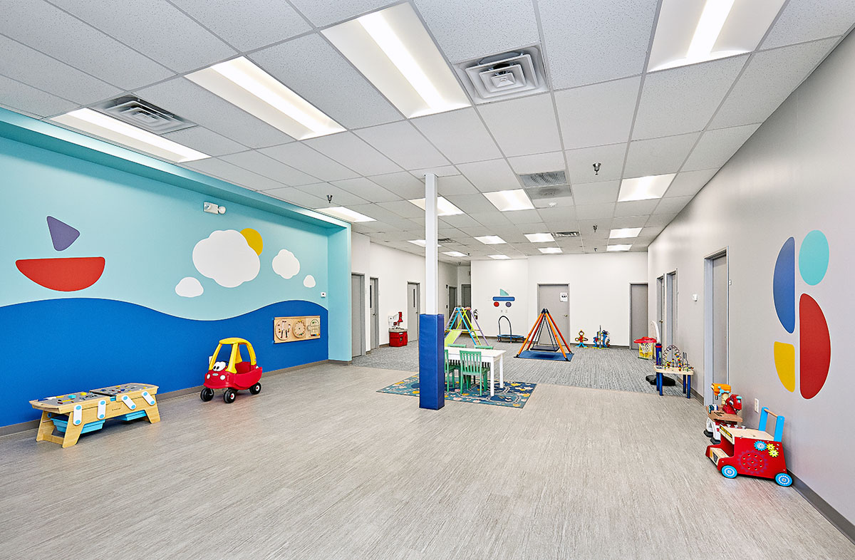 View of interior open space with toys, a table, and multiple doors at the Stride Autism Center near Adel, Iowa.