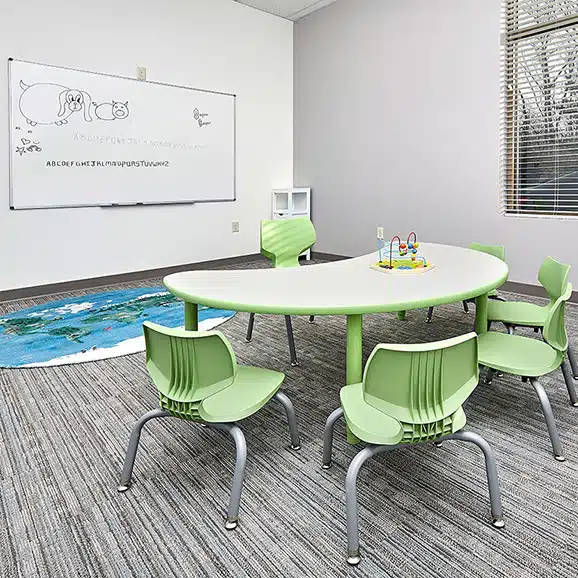 aba-therapy-autism-clinton-iowa-child-treatment-center-52732-stride-centers (1) Classroom with whiteboard, table and chairs where children with autism learn skills during their full-day ABA program near Clinton, Iowa.