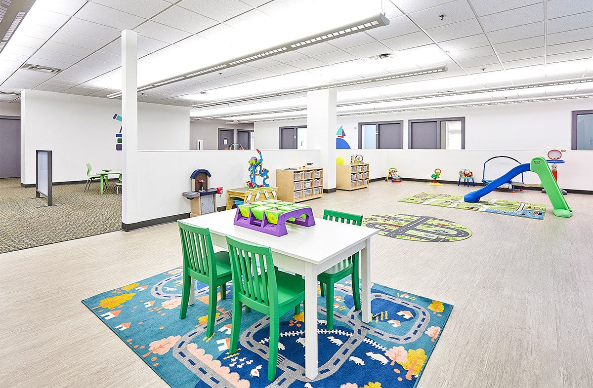 View of interior open space with toys, a table, and multiple doors at the Stride Autism Center near Sheldahl, Iowa.