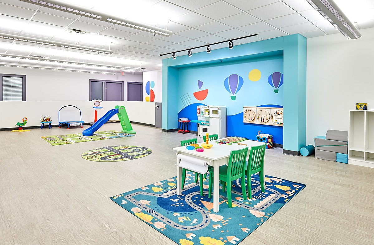View of interior open space with toys, a table, and multiple doors at the Stride Autism Center in Johnston, Iowa.