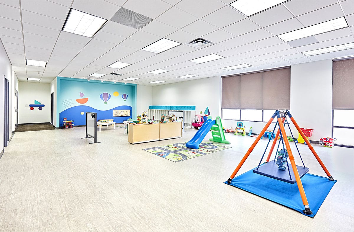 View of interior open space with toys, a table, and multiple doors at the Stride Autism Center near Bettendorf, Iowa.