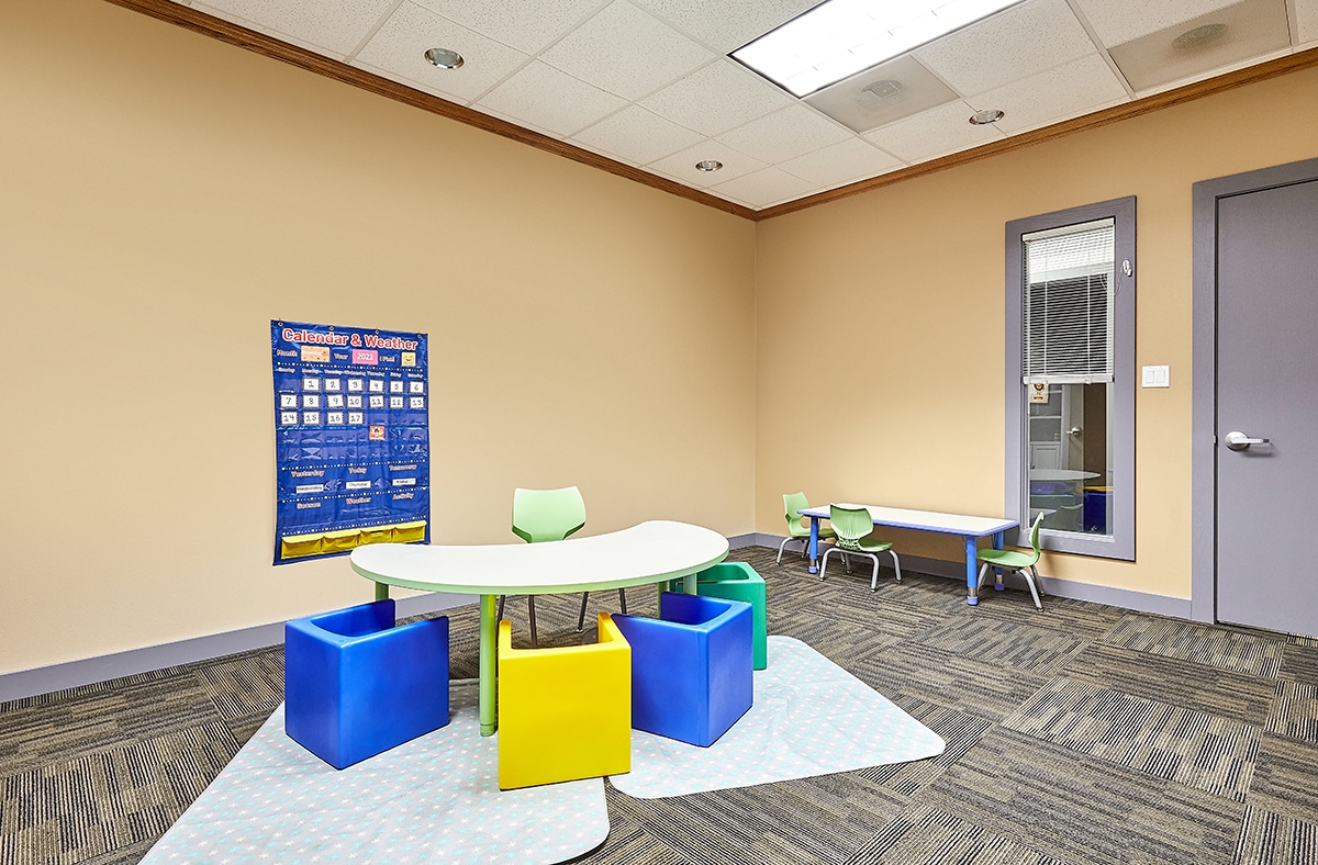Classroom with calendar, tables and chairs where children with autism learn skills during their full-day ABA program near Newhall, Iowa.