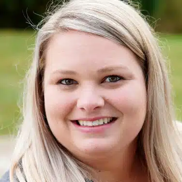 Close-up shot of a woman with straight hair, looking straight at the camera.