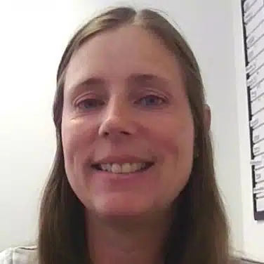 Close-up shot of a woman with wavy hair, looking straight at the camera.