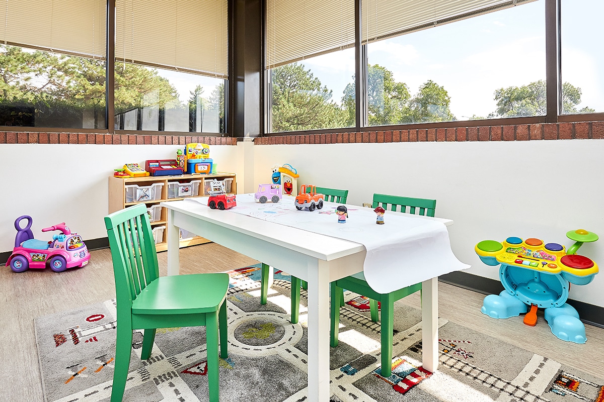 View of interior open space with toys, a table, and windows at the Stride Autism Center near Bennington, Nebraska.