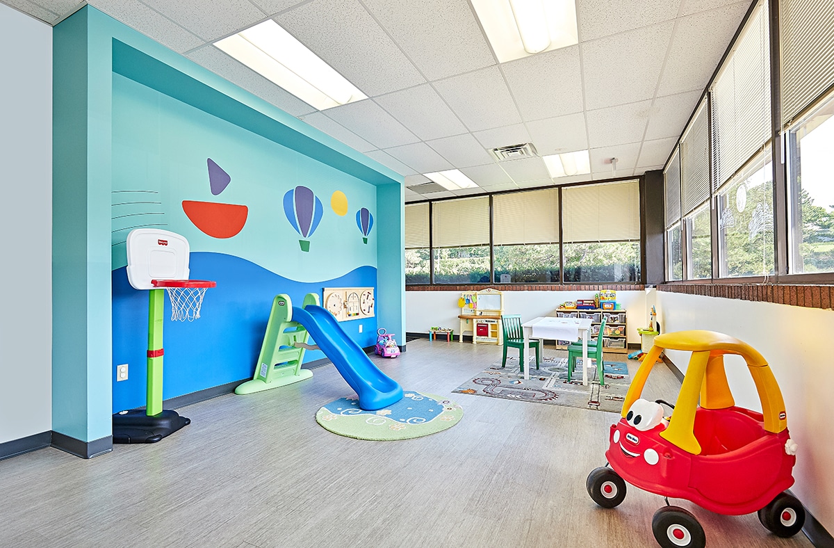 View of interior open space with toys, a table, and windows at the Stride Autism Center near Omaha, Nebraska.