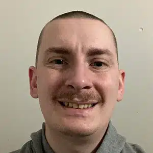 Close-up shot of a man, smiling while looking straight at the camera in front.