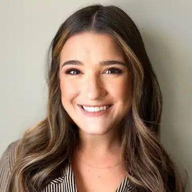 Headshot of a woman with wavy hair, flashing a smile while looking straight at the camera.