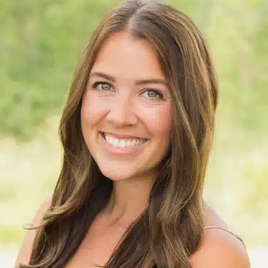 Headshot of a woman with wavy hair, flashing a smile while looking straight at the camera.