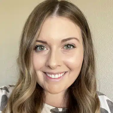 Headshot of a woman with wavy hair, flashing a smile while looking straight at the camera.