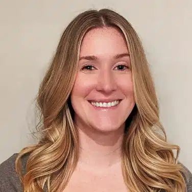 Photo of a woman with wavy shoulder-length hair, looking straight at the camera while smiling.