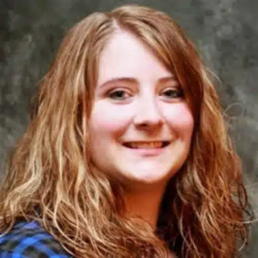 jordan-creed-bcba-davenport-iowa-stride-autism-centers Selfie shot of a woman with curly hair, flashing a close-lipped smile and looking straight at the camera.