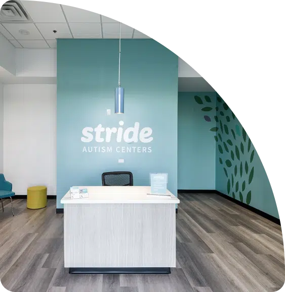 Photo of a reception area with tables and chairs. The wall behind the chair has a signage that reads "Stride Autism Centers."