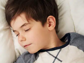 Photo of a boy sleeping. His head is turned to the left.