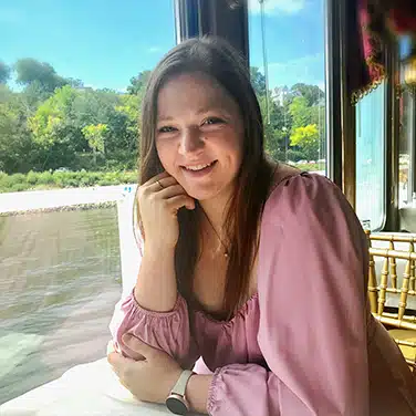 Woman with right elbow on the table and head resting on right hand, while left hand is resting parallel to the table.