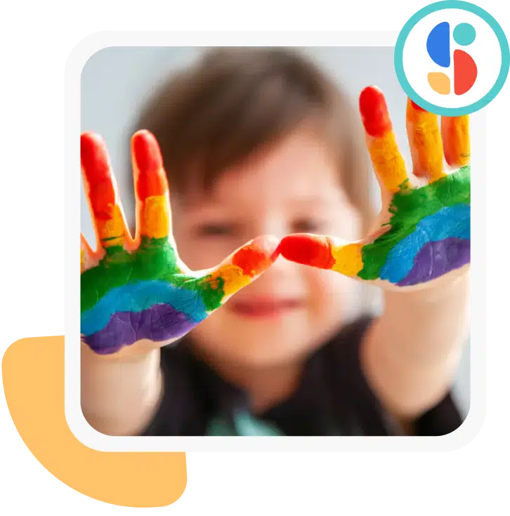 Photo of a toddler with his hands in front of him. The hands is covered with paint of different colors.