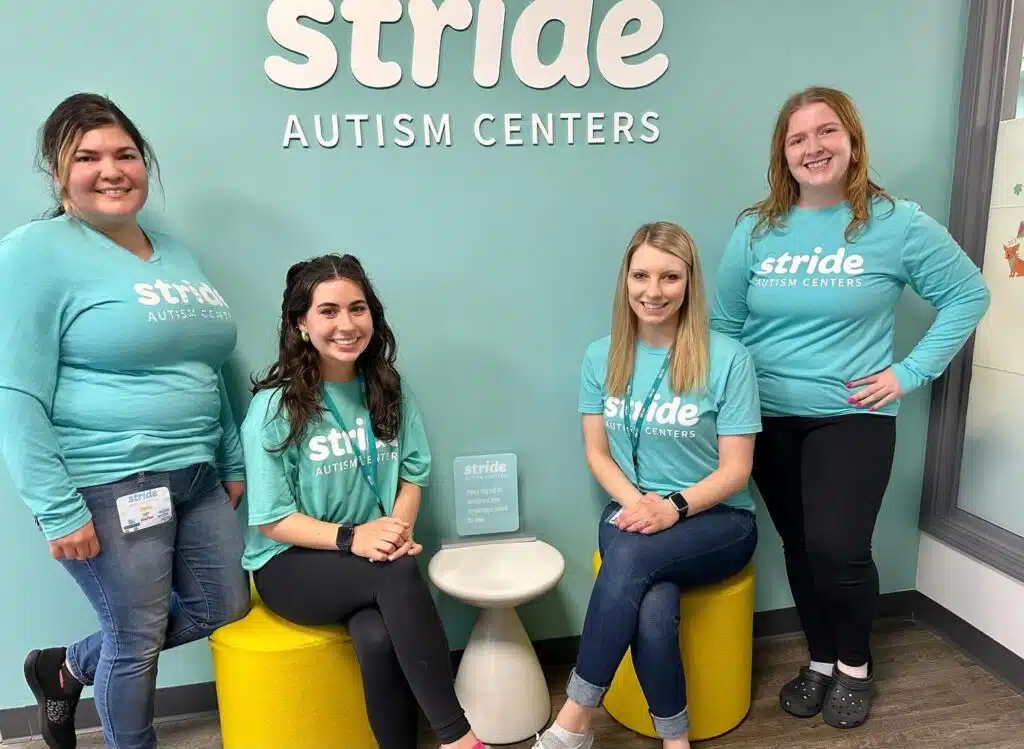 Empleados de Stride Autism Centers® sentados frente al logotipo