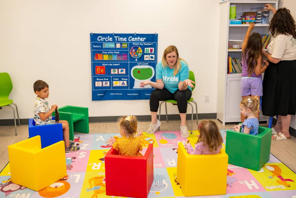 Clinician leads circle time with children in colorful cube chairs at Stride Autism Centers&reg; classroom during ABA therapy.