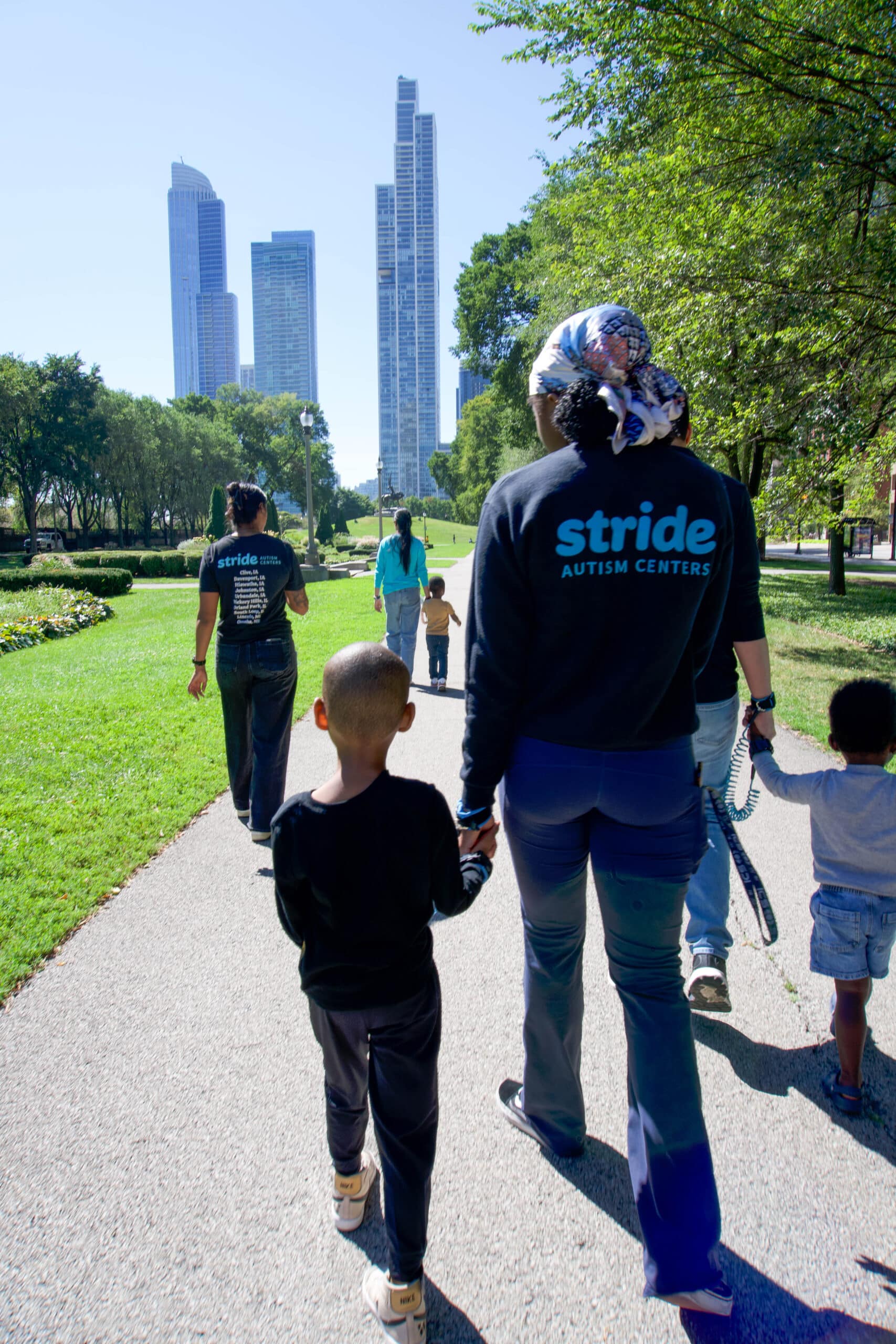 Stride Autism Centers therapists and children walk together in a park, promoting community engagement.