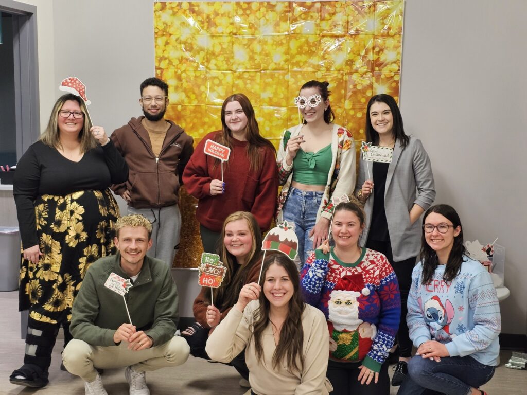 Stride team posing for a holiday photo in colorful sweaters.
