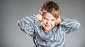 Un niño que se tapa los oídos debido a una sobrecarga sensorial.