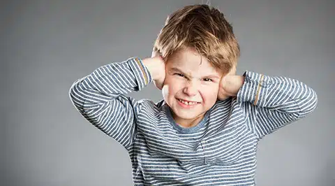 A child covering his ears due to sensory overload.