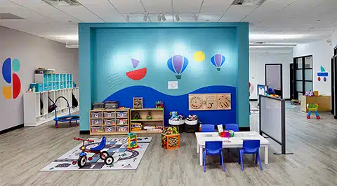 Una simpática terapeuta del Stride Autism Center sonríe mientras trabaja con un niño pequeño en la clínica de Orland Park, Illinois.